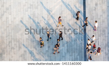 group of people walk on across the pedestrian concrete landscape in the city street (Aerial top view)