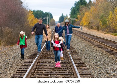 A group of people walking down train tracks on a crisp Autumn day.