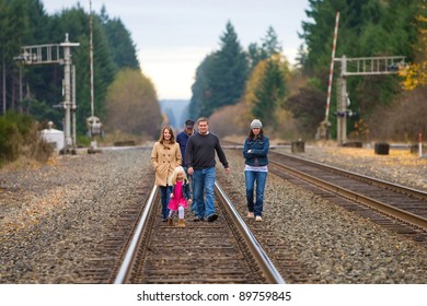 Group of people walking down train tracks outside on an Autumn day.