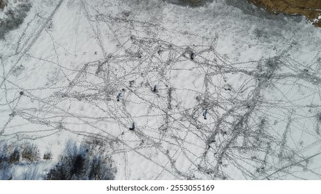 Group of people are walking on a snowy field. The snow is deep and the ground is covered in tracks. Scene is peaceful and serene, as the people are enjoying the winter landscape - Powered by Shutterstock