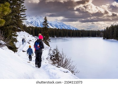 A Group Of People Walking On A Winter Hiking Trail Along Johnson Lake In Banff National Park Canada