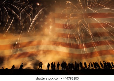 Group Of People Watching Colorful Fireworks In The Sky With American Flag In Background. 4th Of July Concept.