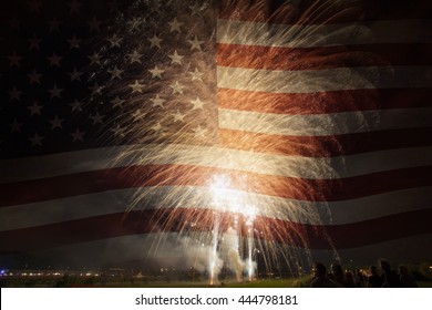 Group Of People Watching Colorful Fireworks In The Sky With American Flag In Background. 4th Of July Concept.