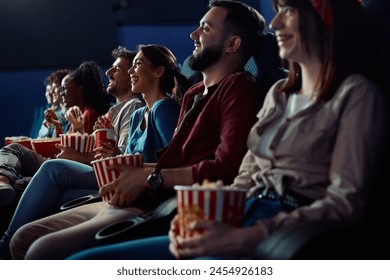 Group of people watching comedy movie in cinema. Focus is on woman laughing and eating popcorn.  - Powered by Shutterstock