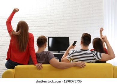 Group Of People Watching TV Together On Sofa In Living Room. Space For Text