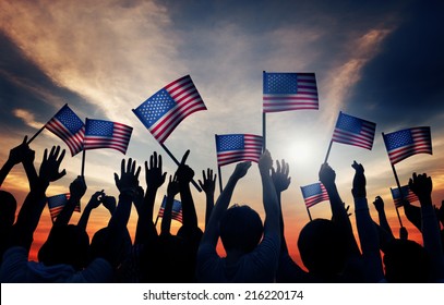 Group Of People Waving American Flags In Back Lit