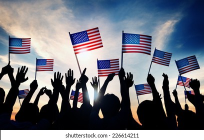 Group Of People Waving American Flags At Sunset