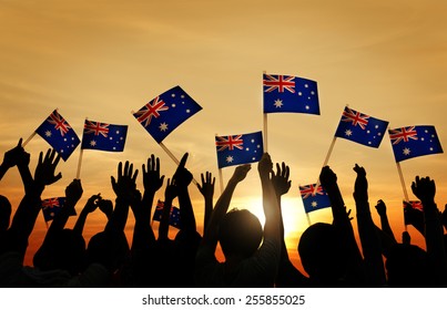 Group Of People Waving Australian Flags In Back Lit