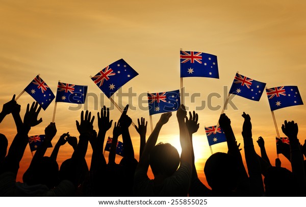 Group of\
People Waving Australian Flags in Back\
Lit