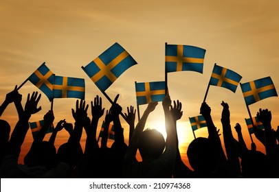 Group Of People Waving Swedish Flags In Back Lit