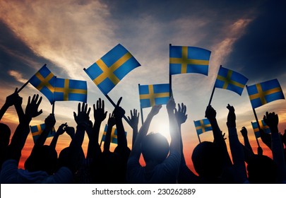 Group Of People Waving Swedish Flags In Back Lit