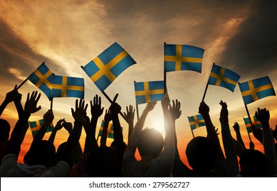 Group of People Waving Swedish Flags in Back Lit Concept