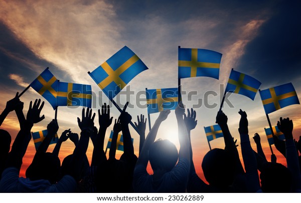 Group of\
People Waving Swedish Flags in Back\
Lit