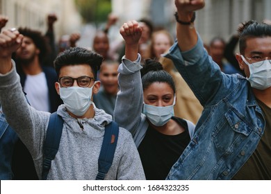 Group of people wearing face mask protesting and giving slogans in a rally. Group of demonstrators protesting in the city.