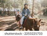 Group of people wearing riding helmets walking on horseback through picturesque places.