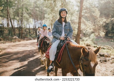 Group of people wearing riding helmets walking on horseback through picturesque places. - Powered by Shutterstock