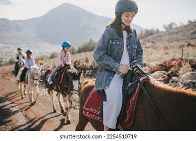 Group of people wearing riding helmets walking on horseback through picturesque places. - Powered by Shutterstock