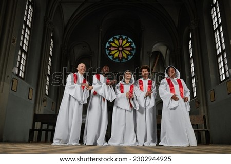 Group of people in white costumes singing in church choir they standing in old church and clapping hands during performance