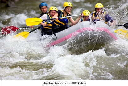 Group Of People Whitewater Rafting And Rowing On River