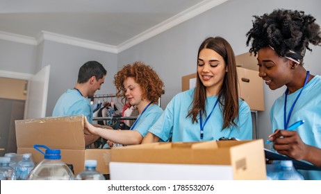 Group Of People Working In Charitable Foundation. Happy Volunteer Looking At Donation Box On A Sunny Day. Happy Volunteer Separating Donations Stuffs. Volunteers Sort Donations During Food Drive