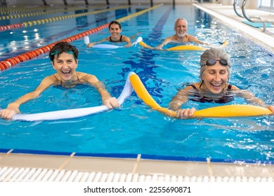 Group of people working with float noodles at water fitness class - Powered by Shutterstock