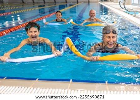 Group of people working with float noodles at water fitness class