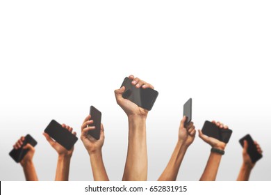 group of people's hands holding phones and rising them up against a white backgroud - Shutterstock ID 652831915