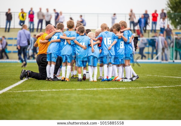 Group pep talk. Coaching youth soccer team before\
the game