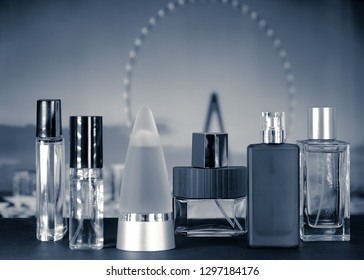 Group of perfume bottles photographed on the table with a ferris wheel background, monochrome interpretation of the shot.