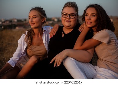 Group Pf Three Friends, Plus Size With Two Thin Girls Spend Happy Time Together And Posing In The Nature. Beautiful Overweight And Strong Women Have Fun, Enjoy The Moment Of Sunset .