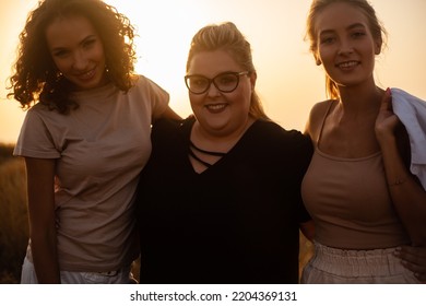 Group Pf Three Friends, Plus Sizewith Two Thin Girls Spend Happy Time Together In The Nature. Beautiful Overweight And Strong Women Have Fun, Enjoy The Momet Of Sunset .