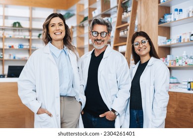 Group of pharmacists standing together and looking at the camera in a chemist. Three healthcare providers working in a pharmacy.