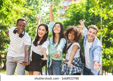 Group Photo. Portrait Of Cheerful Multicultural Students Posing With Raised Hands Outdoors , Having Fun Together In Park