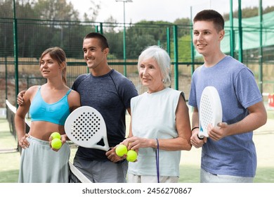 Group photo of positive different aged people standing on padel tennis court after another game. - Powered by Shutterstock