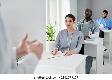 Group Of Physicians Sitting At Desk And Listening To Speaker During Medical Training At Class