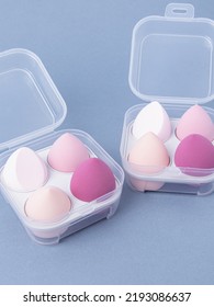 Group Of Pink Makeup Soft Sponges On Blue Background. Makeup Puff In Plastic Case