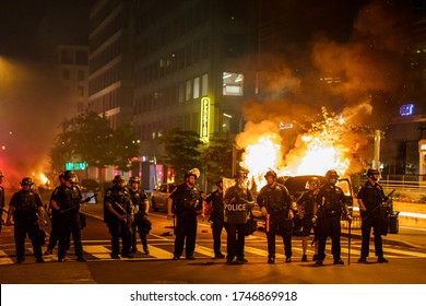 A group of policemen forms a line in front of a burning car. 
Many protesters gathered around in front of White House in Washington DC on 5/30/2020. No justice no peace.