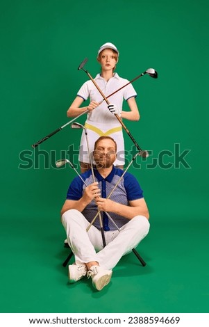 Group portrait of father and daughter on golf court. Dad, man and girl, teenager dressed like golf players posing with golf clubs on green background. Concept of parenthood, hobby, recreation.