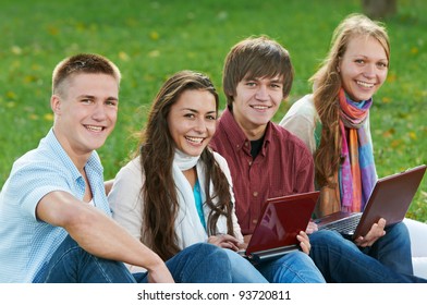 Gruppenporträt von vier lächelnden fröhlichen Studenten im Herbst im Freien