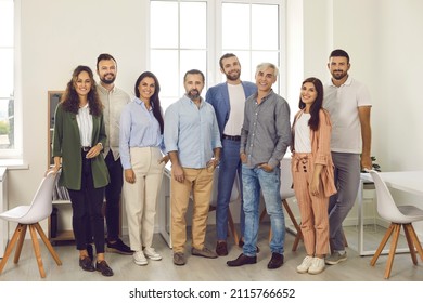 Group portrait of happy confident business professionals and teammates at work. Team of young and mature people in smart casual clothes all together standing in office, looking at camera and smiling