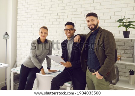 Group portrait of happy confident young diverse co-founders of successful startup company. Team of smiling positive diverse business partners, coworkers or managers standing in office together