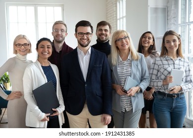 Group portrait of happy diverse colleagues of different ages. United businesspeople of 30s and 50s looking at camera. Team of trainee interns and coaches posing together in office. Teamwork concept