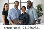 Group portrait of happy multiethnic united millennial team in modern office. Successful employees standing together, meeting in workspace, looking at camera and smiling Team work concept. Head shot