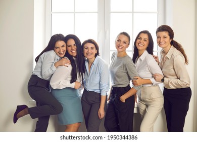 Group Portrait Of Happy Positive Successful Business Women. Team Of Cheerful Young Female Company Employees In Their 20s And 30s Standing Close Together By Office Window And Smiling At Camera