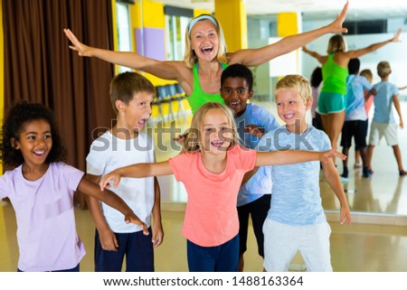 Group portrait of happy tweenagers with female choreographer in modern dance studio 
