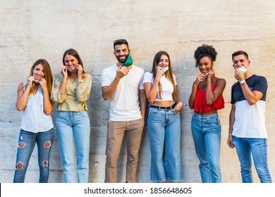 Group portrait of multi-ethnic boys and girls with colorful fashionable clothes holding friend and posing on wall wearing face mask for coronavirus - Urban style people having fun - Concepts youth a - Shutterstock ID 1856648605