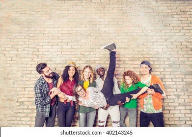 Group Portrait Of Multi-ethnic Boys And Girls With Colorful Fashionable Clothes Holding Friend And Posing On A Brick Wall - Urban Style People Having Fun - Concepts About Youth  And Togetherness