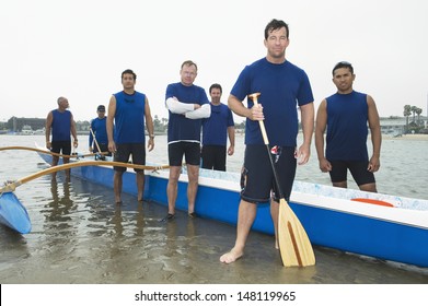 Group portrait of multiethnic outrigger canoeing team on beach