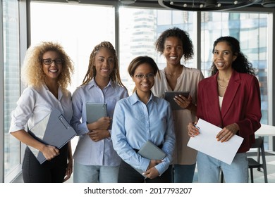 Group Portrait Of Smiling Beautiful Young African American Multiracial Business Women Colleagues Employees Professionals Looking At Camera, Happy Corporate Workers Posing In Modern Workplace.