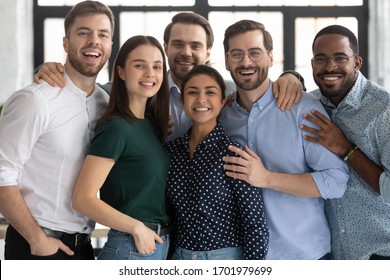 Group Portrait Of Smiling Diverse Multiracial Young Businesspeople Posing Together In Office, Happy Multiethnic Millennial Colleagues Look At Camera Show Unity And Support At Work, Teamwork Concept